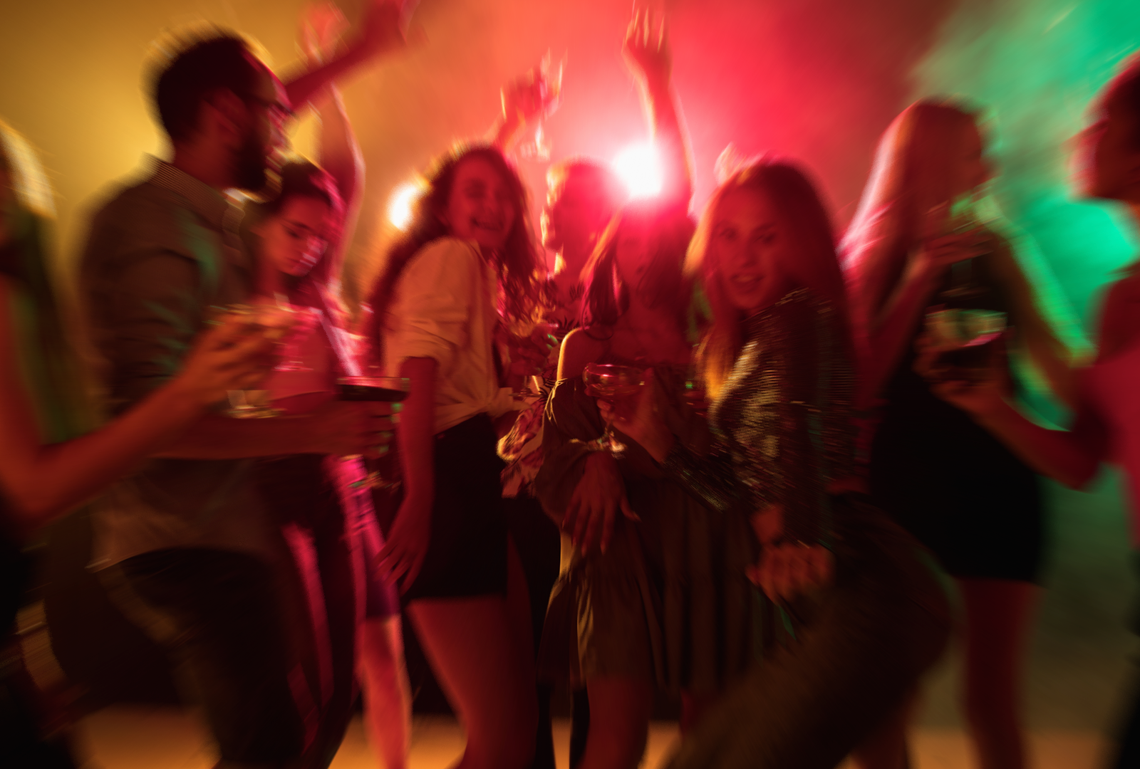 Photo of a nightclub with people dancing under coloured lights.